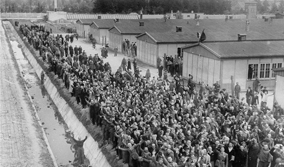 una gran cantidad de prisioneros exultantes, saludando a sus libertadores delante de la fosa de agua (Derechos de imagen: USHMM)