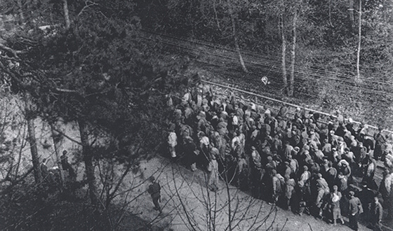 Prisioneros que caminan agotados en una marcha grande por una calle (Derechos de imagen: Archivo municipal de Landsberg am Lech).